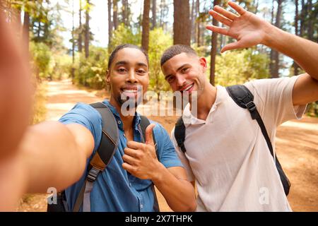 POV photo de deux amis masculins marchant le long de Trail dans la campagne posant pour Selfie sur téléphone portable Banque D'Images