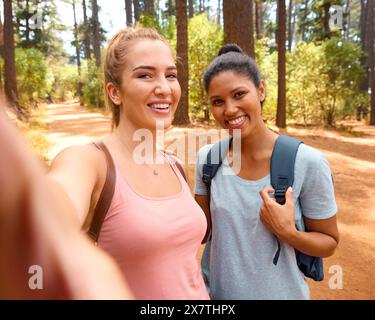 POV photo de deux amies femmes marchant le long de Trail dans la campagne posant pour Selfie sur téléphone portable Banque D'Images