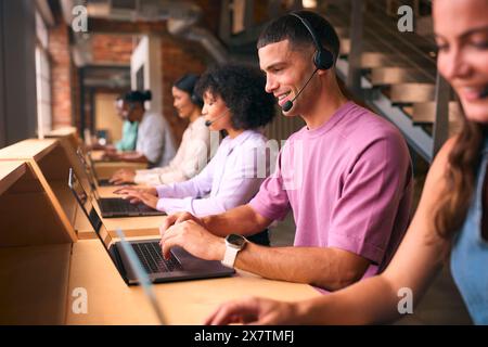 Équipe d'assistance client multiculturelle ou de télévente dans un bureau moderne ouvert portant des micro-casques Banque D'Images