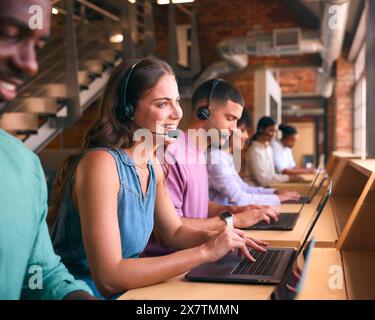 Équipe d'assistance client multiculturelle ou de télévente dans un bureau moderne ouvert portant des micro-casques Banque D'Images