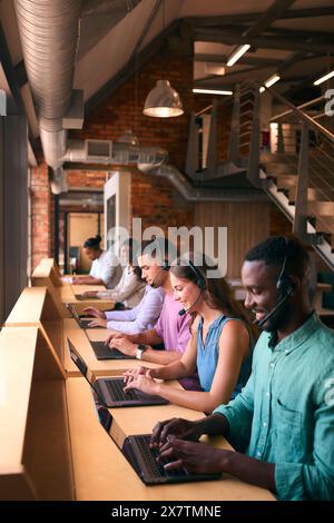 Équipe d'assistance client multiculturelle ou de télévente dans un bureau moderne ouvert portant des micro-casques Banque D'Images