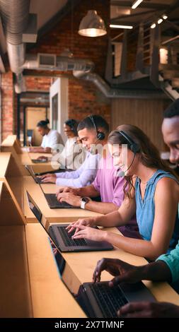 Équipe d'assistance client multiculturelle ou de télévente dans un bureau moderne ouvert portant des micro-casques Banque D'Images