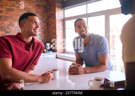 Hommes d'affaires multiculturels prenant une pause café dans la zone de cuisine du bureau moderne ouvert ensemble Banque D'Images