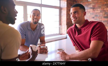 Hommes d'affaires multiculturels prenant une pause café dans la zone de cuisine du bureau moderne ouvert ensemble Banque D'Images