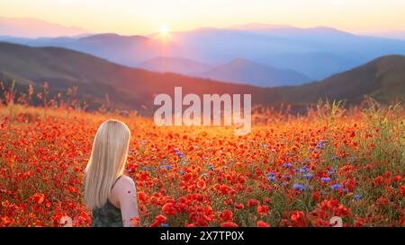 Tyrol. Autriche ; 21 mai 2024 - Une jeune femme debout dans un champ coloré de coquelicots sauvages au Tyrol, Autriche Banque D'Images