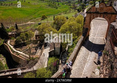 Les touristes se tiennent sur le vieux pont près de l'arche Felipe V regardant vers le bas vers l'ancien pont arabe et les thermes romains, le long de la vieille muraille de la ville à Ronda, province de Malaga, Espagne. Banque D'Images