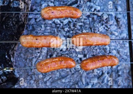 Saucisses frites sur brochettes. Soirées d'été près du feu, bon week-end. Gros plan Banque D'Images