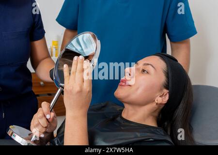 La jeune femme observe ses lèvres après avoir reçu un traitement par botox Banque D'Images