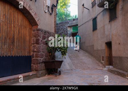 05-10-2024, Prades, Espagne : ruelle avec touriste marchant à travers la ville et brouette de construction comme un jardin Banque D'Images