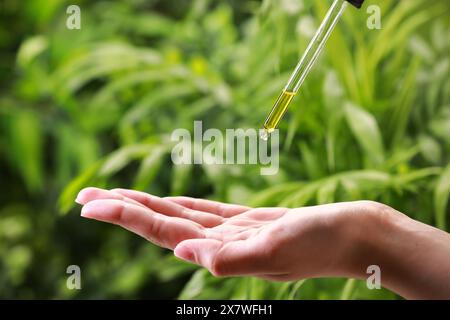 Femme gouttant de l'huile essentielle de pipette à l'extérieur, gros plan Banque D'Images