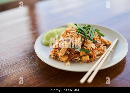 Nourriture, assiette et cuisine chinoise avec baguettes à manger avec poulet, nouilles et plat à l'oignon de printemps. Déjeuner, pad thaï et sautés authentiques pour les Asiatiques Banque D'Images