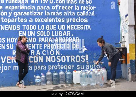 Deux femmes d'un campement de migrants dans le quartier de Misterios à Mexico remplissant de grandes cruches d'eau. Banque D'Images