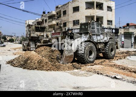 Jénine, Palestine. 21 mai 2024. Un bulldozer militaire israélien détruit l'infrastructure du camp de réfugiés de Djénine, dans le nord de la Cisjordanie, au cours d'une opération militaire à la recherche de militants palestiniens de la brigade de Djénine. Dans le camp du nord de la Cisjordanie, au cours d'une opération militaire à la recherche de militants palestiniens de la brigade de Djénine. Le ministère palestinien de la santé a déclaré que 7 civils palestiniens avaient été tués, dont deux médecins, un enseignant et un étudiant qui se rendait à l’école pendant l’opération militaire. Crédit : SOPA images Limited/Alamy Live News Banque D'Images