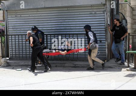 Jénine, Palestine. 21 mai 2024. Les journalistes portent leur collègue blessé par les balles des forces israéliennes lors d'une opération militaire dans le camp de réfugiés de Djénine. Dans le camp du nord de la Cisjordanie, au cours d'une opération militaire à la recherche de militants palestiniens de la brigade de Djénine. Le ministère palestinien de la santé a déclaré que 7 civils palestiniens avaient été tués, dont deux médecins, un enseignant et un étudiant qui se rendait à l’école pendant l’opération militaire. Crédit : SOPA images Limited/Alamy Live News Banque D'Images