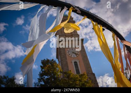 Des rubans de tissu jaunes et bleus flottent dans le vent sur le fond d'un ciel bleu et d'une ancienne tour de l'horloge. Banque D'Images