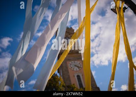 Des rubans de tissu jaunes et bleus flottent dans le vent sur le fond d'un ciel bleu et d'une ancienne tour de l'horloge. Banque D'Images