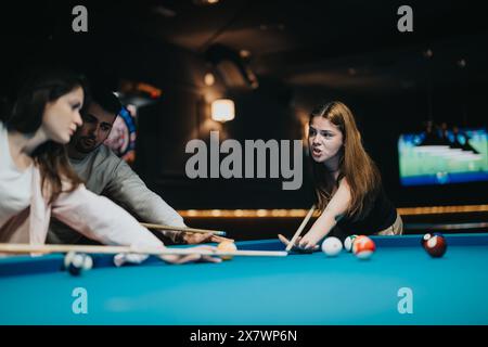 Jeunes amis s'amusant à jouer un jeu compétitif de billard dans un club confortable Banque D'Images