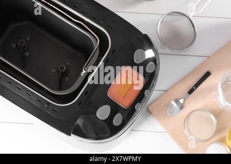 Machine à pain et différents produits sur table en bois blanc, pose à plat Banque D'Images