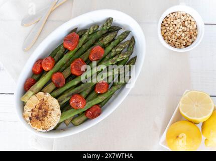 Asperges vertes cuites dans un plateau blanc et servies comme plat d'accompagnement prêt à manger. Représentant une source de grandes fibres alimentaires. Banque D'Images