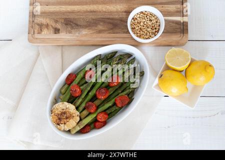 Asperges vertes cuites dans un plateau blanc et servies comme plat d'accompagnement prêt à manger. Représentant une source de grandes fibres alimentaires. Banque D'Images