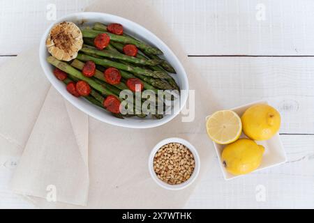 Asperges vertes cuites dans un plateau blanc et servies comme plat d'accompagnement prêt à manger. Représentant une source de grandes fibres alimentaires. Banque D'Images