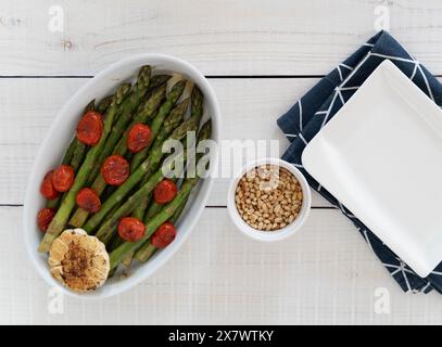 Asperges vertes cuites dans un plateau blanc et servies comme plat d'accompagnement prêt à manger. Représentant une source de grandes fibres alimentaires. Banque D'Images