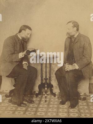 Photographie antique c1890, frères buvant du whisky ensemble. Ils sont séparés de sept ans, mais ressemblent à des jumeaux. Emplacement exact inconnu, probablement Massachusetts ou Rhode Island, USA. SOURCE : PHOTOGRAPHIE ORIGINALE Banque D'Images