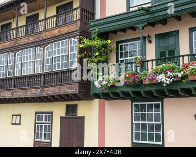 Balcons en bois de style colonial avec des plantes et des fleurs sur une façade beige-brun, balcon en bois avec des décorations florales sur des maisons historiques, l Banque D'Images