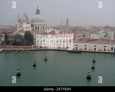 Vue sur les bâtiments vénitiens avec des dômes et des toits oranges, l'eau et l'atmosphère brumeuse, les tours d'église et les bâtiments historiques sur un grand canal, vue sur Ven Banque D'Images