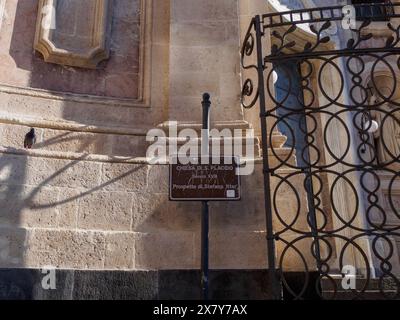 Panneau près d'une église avec une porte de fer et des murs de pierre, partiellement dans l'ombre, mettant en valeur l'architecture historique, Catane, italie, 3 février 2024, 3 d Banque D'Images