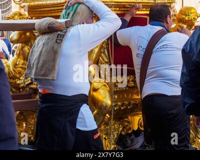 Deux hommes en chemises blanches portent une lourde structure dorée lors d’un défilé traditionnel, mettant en valeur le travail d’équipe et l’effort, Catane, italie, 3 février 2024, Banque D'Images