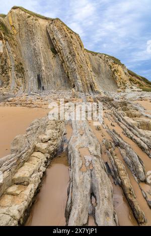 Des formations rocheuses sédimentaires érosives fantaisistes sur Portio Beach avec son sable doré et ses couches de roche. Géoparc Costa Quebrada, Cantabrie, Espagne. Banque D'Images