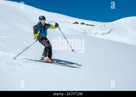 Ski alpiniste avec casque et sac à dos descendant dans la neige fraîche Banque D'Images