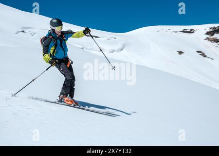 Ski alpiniste avec casque et sac à dos descendant dans la neige fraîche Banque D'Images