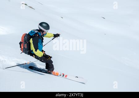 Ski alpiniste avec casque et sac à dos descendant dans la neige fraîche Banque D'Images