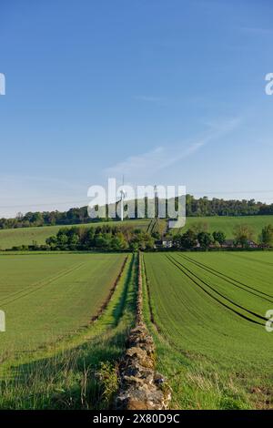 Des pylônes électriques et une éolienne commerciale traversant la colline de terres agricoles près du village de Memus à la périphérie de l'Angus Glens. Banque D'Images