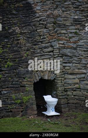 April Fools Fun avec une toilette à la base de l'une des tours du mur du château de Caerphilly au début du printemps, pays de Galles Banque D'Images