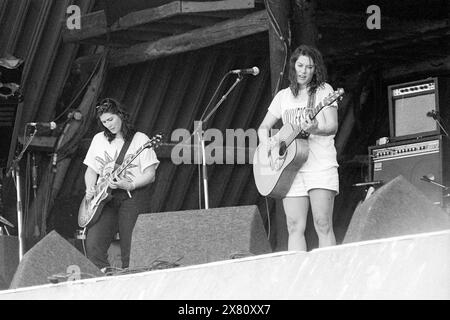 KIM DEAL, KELLEY DEAL, THE BREEDERS, PYRAMID STAGE, GLASTONBURY 92 : Kim Deal des Breeders jouant de la guitare acoustique avec sa sœur jumelle Kelley Deal (guitare électrique) sur la Pyramid Stage au Glastonbury Festival, Pilton, Angleterre, 26 juin 1992. Les poutres en bois de la scène Pyramid originale sont visibles. Cette étape a brûlé en 1994. Photographie : ROB WATKINS. INFO : The Breeders est un groupe de rock alternatif américain formé en 1989 par Kim Deal des Pixies et Tanya Donelly de Throwing Muses. Connus pour leur son brut et leur succès « Cannonball », ils sont devenus des figures influentes du rock indépendant des années 1990 Banque D'Images