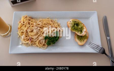 Délicieux spaghetti carbonara avec pain à l'ail et boisson dans un restaurant italien pour le déjeuner Banque D'Images