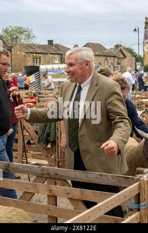 Juge masculin mature souriant, debout à côté d'un enclos en bois pour animaux sur la place à Masham, à la foire annuelle des moutons. North Yorkshire, Royaume-Uni Banque D'Images