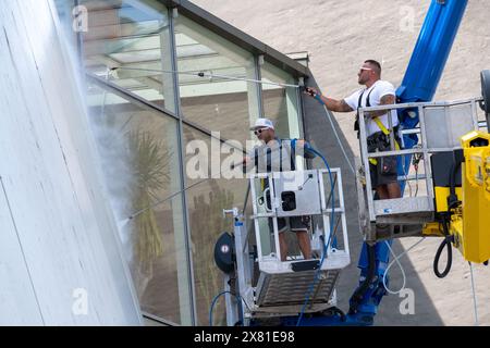 Stralsund, Allemagne. 22 mai 2024. Les employés de l'entreprise de nettoyage de façades FassadenFix de Halle/Saale nettoient la façade du musée faite de grands panneaux de construction navale en acier. Les 360 panneaux en acier incurvés blancs de l'Ozeaneum couvrent une superficie d'environ 3800 mètres carrés et atteignent des hauteurs allant jusqu'à 24 mètres. Huit employés de FassadenFix effectuent le nettoyage en utilisant quatre bus de lavage et trois plates-formes spéciales - dont certaines mesurent jusqu'à 51 mètres de haut. Crédit : Stefan Sauer/dpa/ZB/dpa/Alamy Live News Banque D'Images