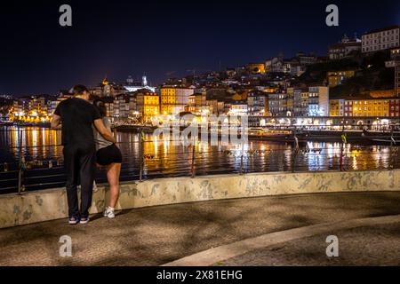 Jeune couple sur le quai vers Cais da Ribeira la nuit, Porto, Portugal Banque D'Images