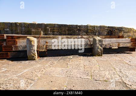 Planches de bois recouvertes d'acier rouillé utilisées comme défenses maritimes à l'entrée du port. Le pittoresque village de pêcheurs de Mousehole, Cornouailles, West Country, E. Banque D'Images