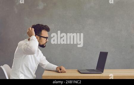 Photo de tête d'un homme d'affaires caucasien confus sérieux et perplexe utilisant un ordinateur portable Banque D'Images