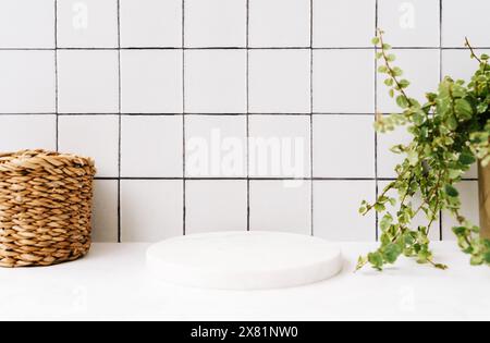 Podium rond en marbre blanc pour produits de bain dans la vue avant de la salle de bain, paille et plante verte dans le pot sur étagère en marbre blanc et carreaux muraux. Copier l'espace. Banque D'Images
