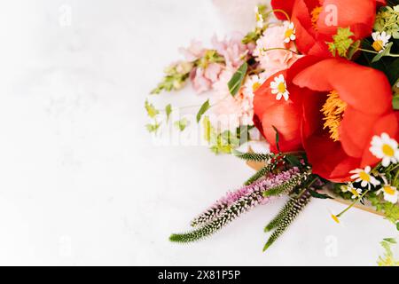 Beau bouquet avec pivoine rouge et autres fleurs sur table blanche avec espace de copie pour votre texte vue de dessus et style plat de pose Banque D'Images