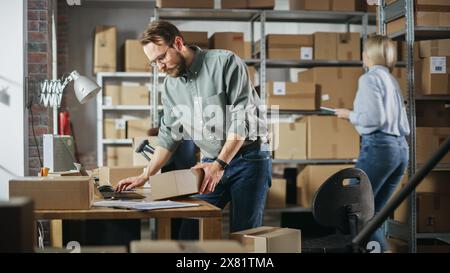 Équipe multiculturelle d'employés d'entrepôt au travail dans l'entrepôt du magasin de détail. Propriétaires de petites entreprises et gestionnaires d'inventaire travaillant sur un ordinateur portable, emballant des colis pour la livraison. Banque D'Images