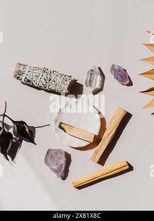 Sauge blanche et Palo Santo et améthyste et cristaux de quartz sur fond beige clair. Vue de dessus. Un ensemble d'encens pour la fumigation. Banque D'Images