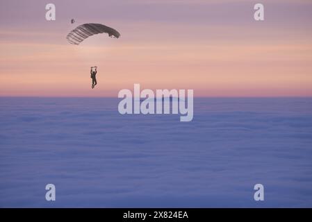 Parapente survolant un paysage nuageux avec un pic de montagne au coucher du soleil au Tessin, Suisse. Banque D'Images