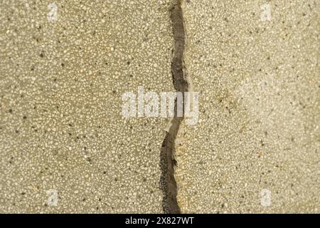 Une vue rapprochée d’un mur de béton fissuré, mettant en valeur la texture et l’abstraction de la surface de la pierre. Banque D'Images